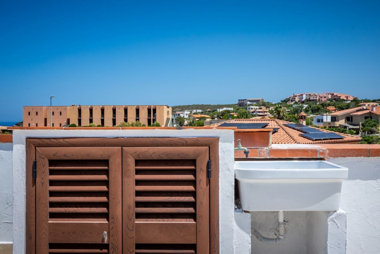 Un edifici amb façana blanca, una finestra amb persianes de fusta i un rentamics blanc.