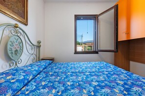 Ein Schlafzimmer mit einem Bett, einem Fenster und Blick auf Gebäude.