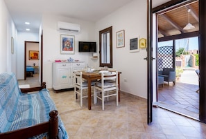 Une chambre avec un lit, un coin repas avec une table et des chaises, un appareil de climatisation et un téléviseur.