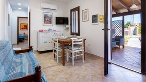 A bedroom with a bed, a dining area with a table and chairs, an air conditioning unit, and a TV. - GuestHost - Cozy detached house of about 60 sqm, perfect for 4 people, located on the ground floor.The property is located in Torre dei Corsari, a charming village overlooking the splendid Costa Verde of Sardinia. In a few minutes by car you can reach so (Torre dei Corsari)