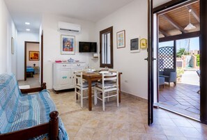 Ein Schlafzimmer mit Bett, Essecke mit Tisch und Stühlen, Klimaanlage und Fernseher.