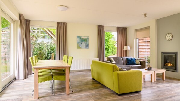 A living room with a dining table, green sofa, and a fireplace.