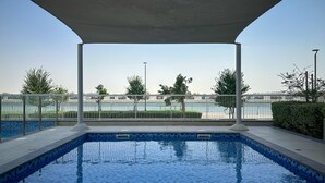 Piscina al aire libre con vistas a una masa de agua y un puente al fondo.