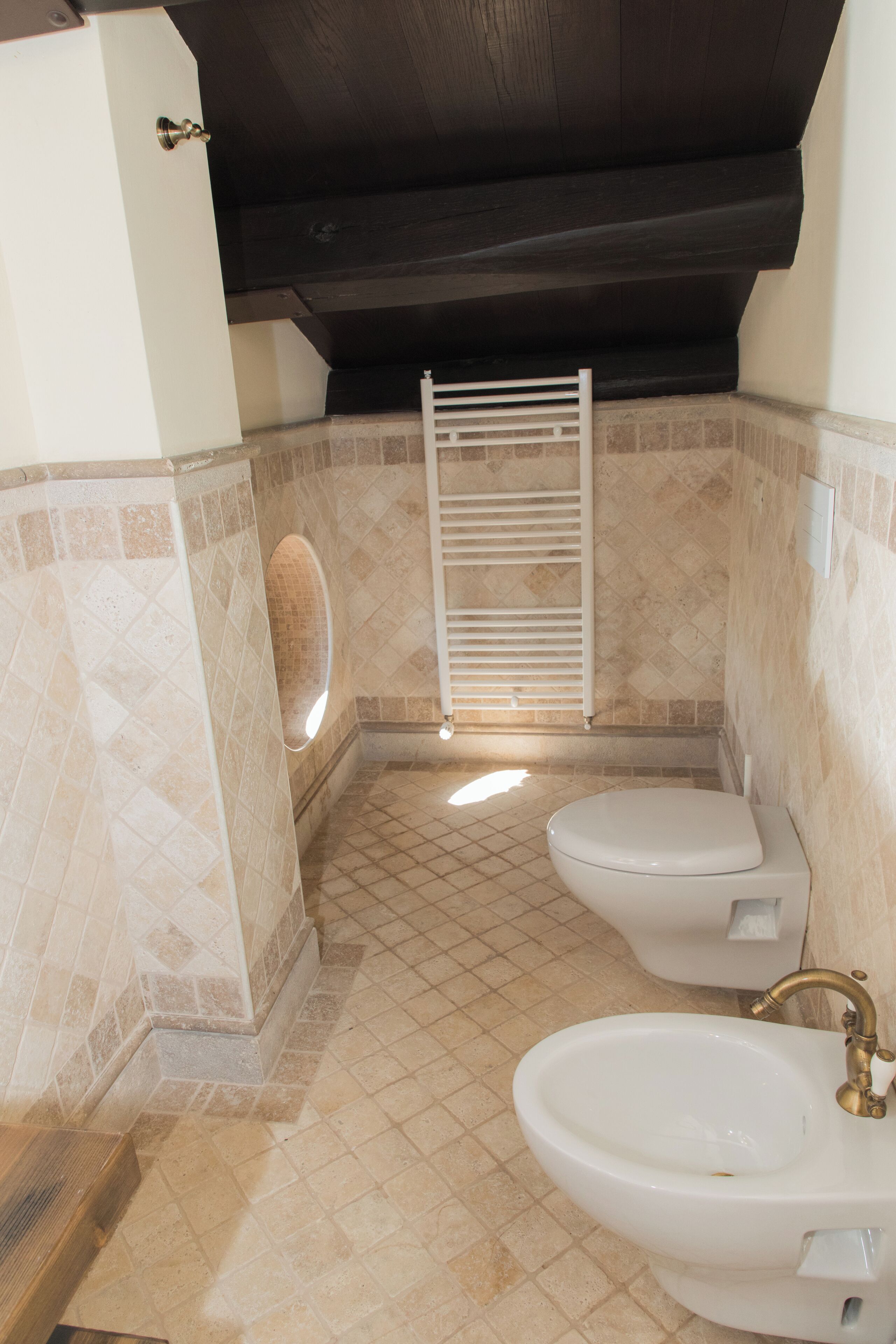 A bathroom with two toilets, a sink, and a shower area with a towel rack.