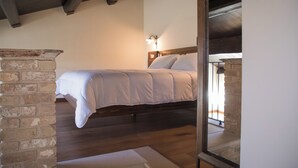 A bedroom with a bed, wooden floor, brick wall, and a nightstand. - Casale Madonna Grande (Campomarino)