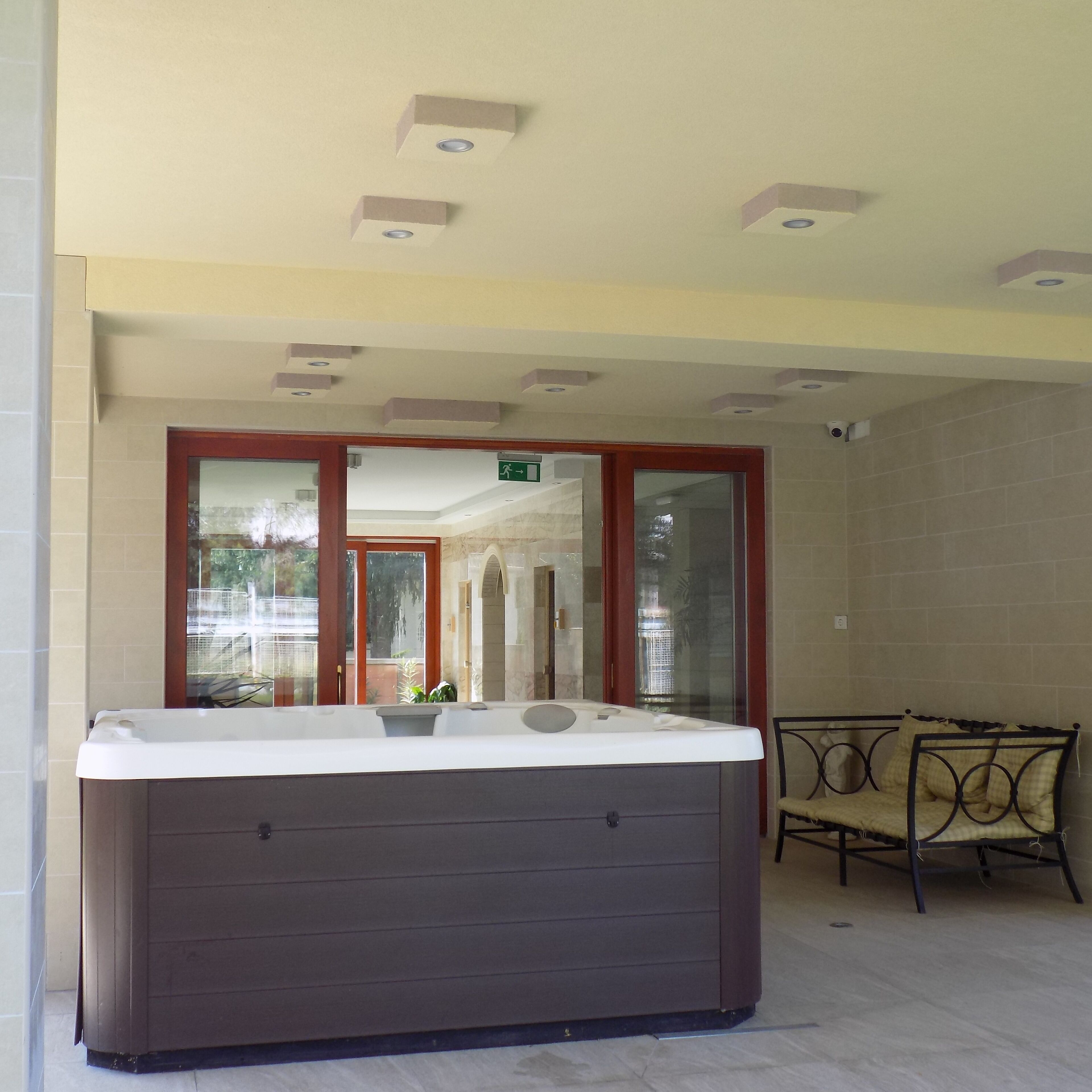 A spa area with a hot tub, a glass-enclosed window, and a metal chair.