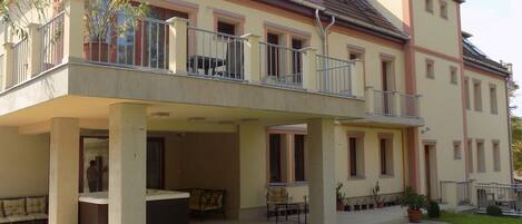 A two-story house with a balcony, a patio area with outdoor furniture, and a well-maintained lawn.