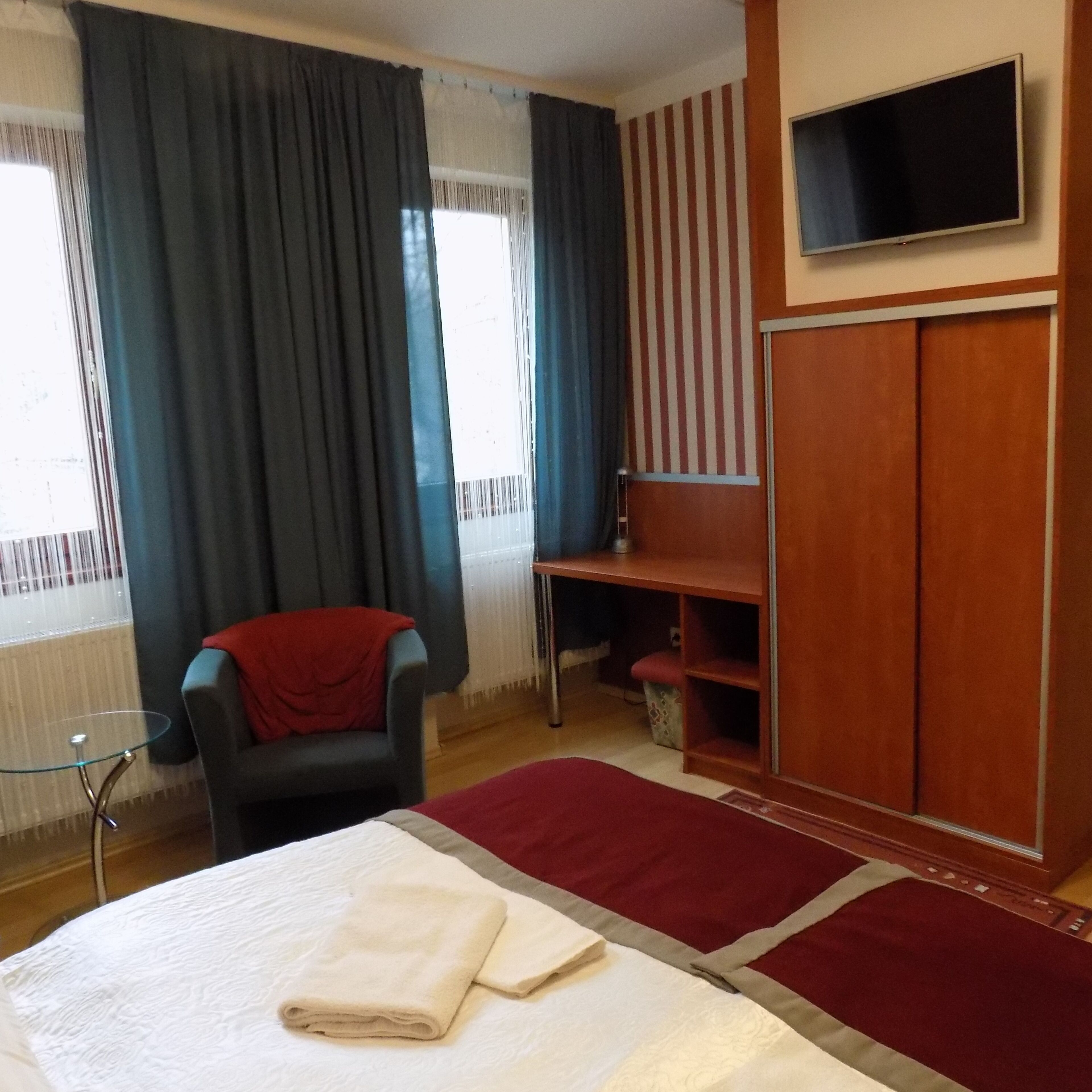 Een hotelkamer met een bed, een stoel, een aan de muur bevestigde televisie en een kledingkast.