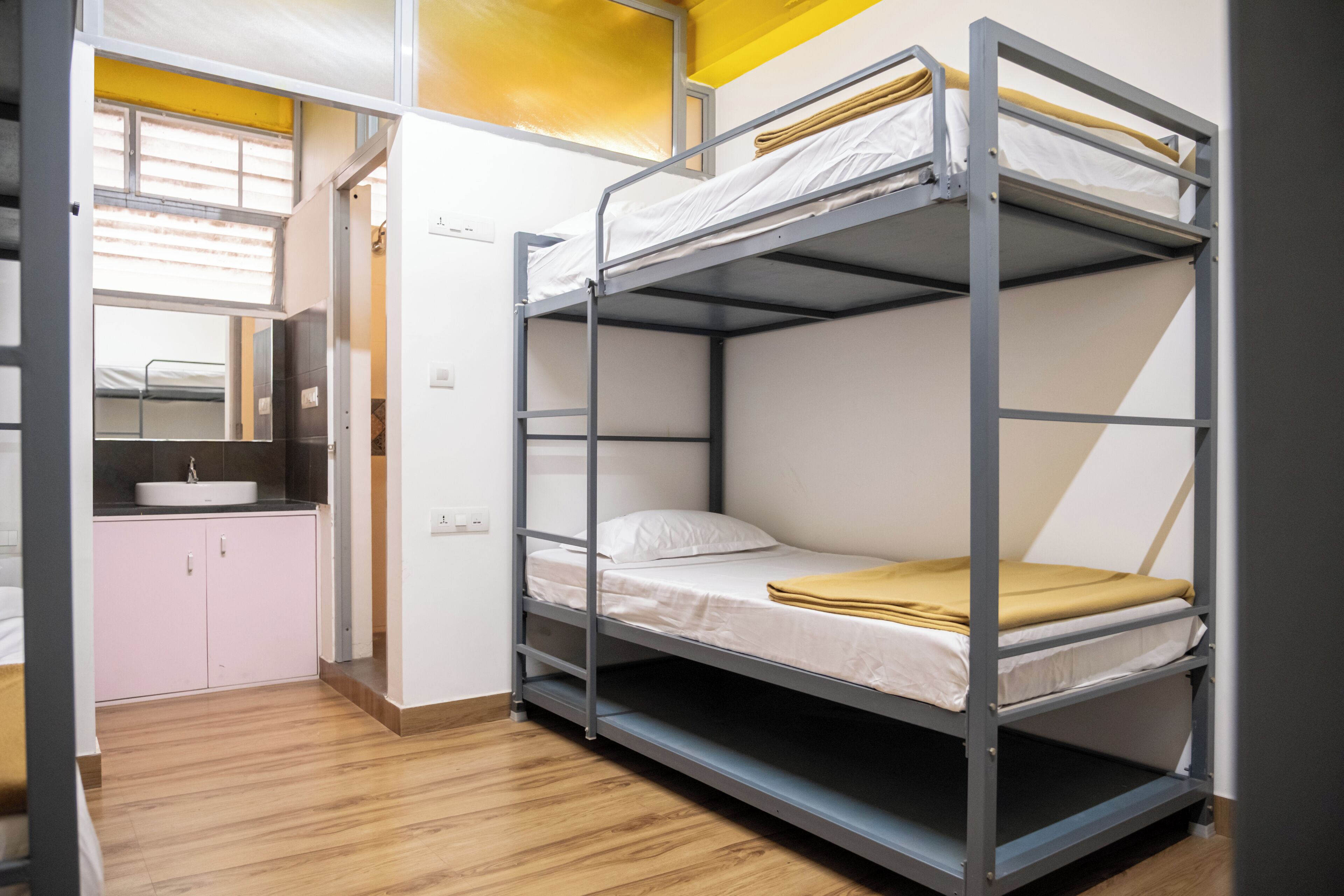 A bunk bed with a sink and a small cabinet in a room with wooden flooring.