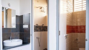 A bathroom with a sink, mirror, shower, and toilet. - Stopover Backpackers Stay (Bengaluru)