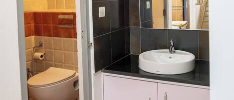 A bathroom with a toilet, sink, and cabinet.
