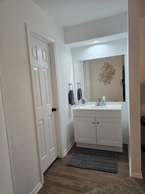 Une salle de bain avec un meuble-lavabo blanc, un miroir et un porte-serviettes.