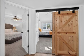 Un dormitorio con cama, mesita de noche, lámpara y ventilador de techo.