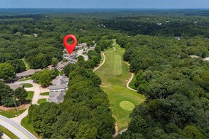 Eine Vogelperspektive eines Wohngebiets mit einem Golfplatz, umgeben von dichtem Wald.