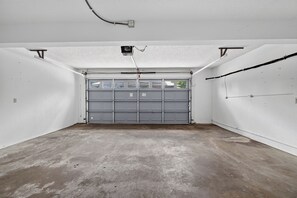 Een garage met een grijze deur, witte muren en een betonnen vloer.