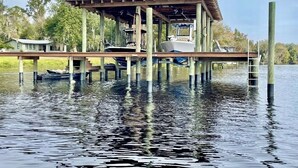 Un muelle de madera con una zona de estar techada y un bote.