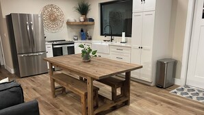 Una cocina moderna con una mesa de comedor de madera, electrodomésticos de acero inoxidable y armarios blancos.