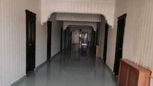A spacious, well-lit hallway with a tiled floor, flanked by walls with vertical lines and a central arched structure.