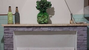 Una repisa de chimenea con dos botellas y un florero verde.