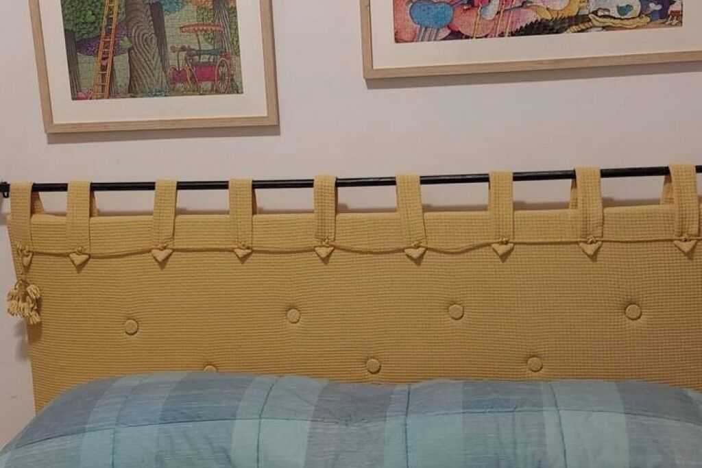 A bed with a yellow headboard and a blue blanket.