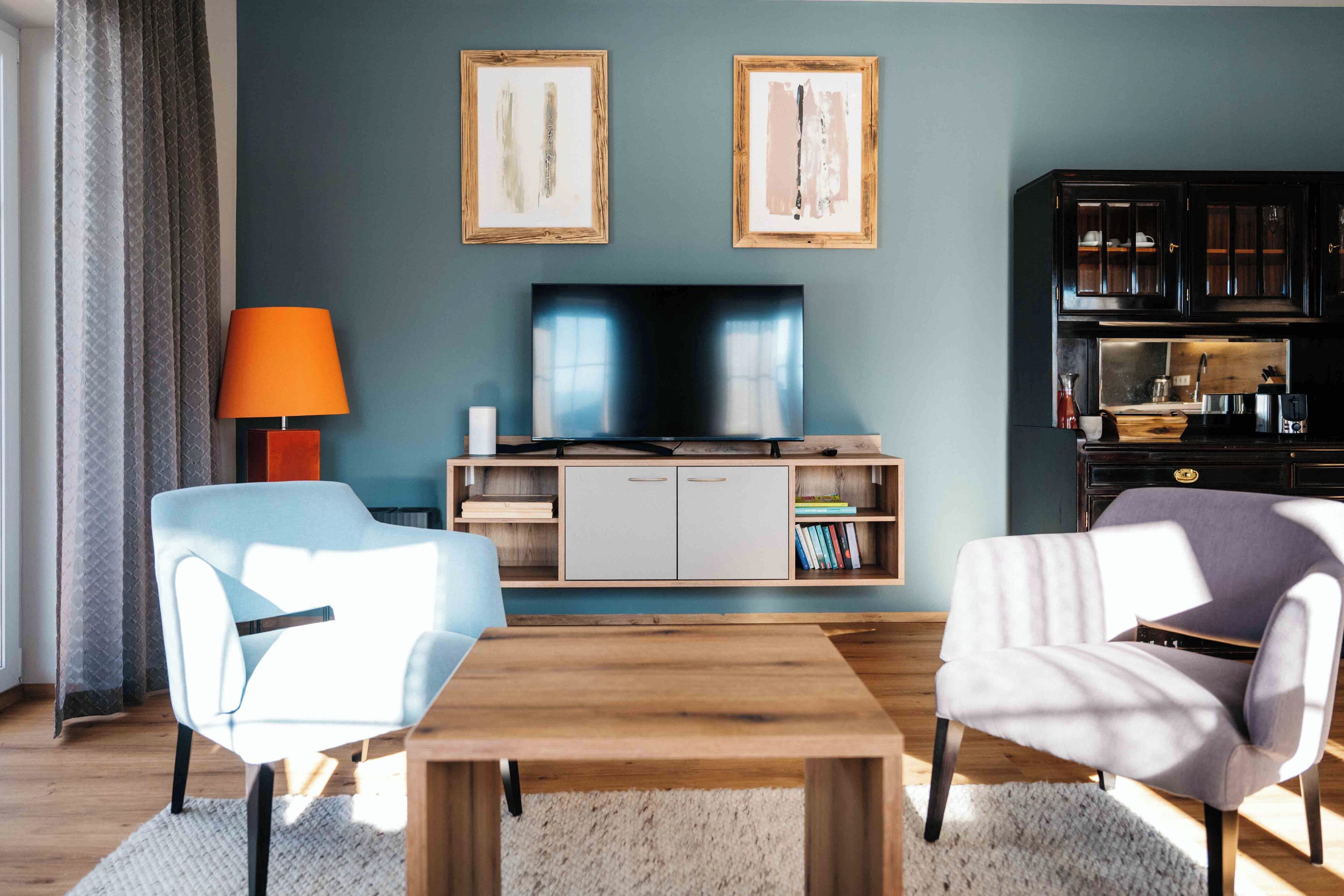 A living room with a TV, two chairs, a coffee table, and a bookshelf.