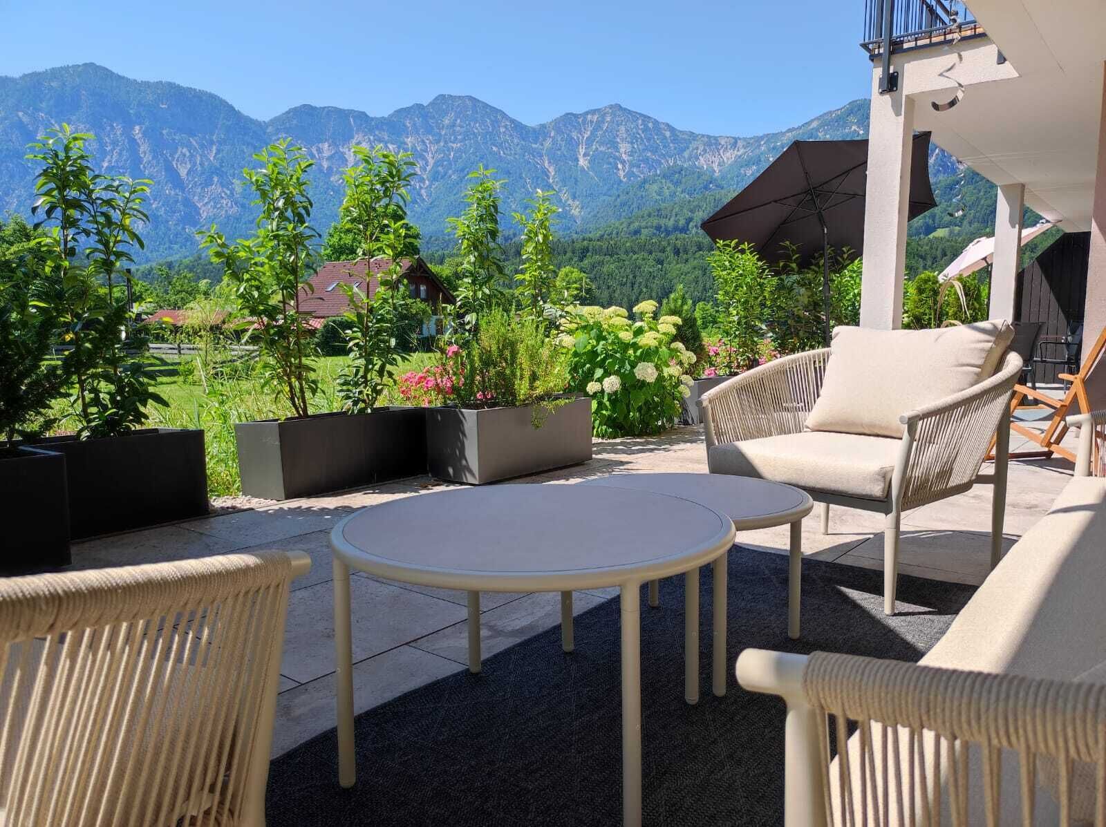 An outdoor patio with wicker furniture, a round table, and potted plants.