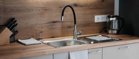 A modern kitchen with a wooden countertop, stainless steel sink, and a coffee maker.