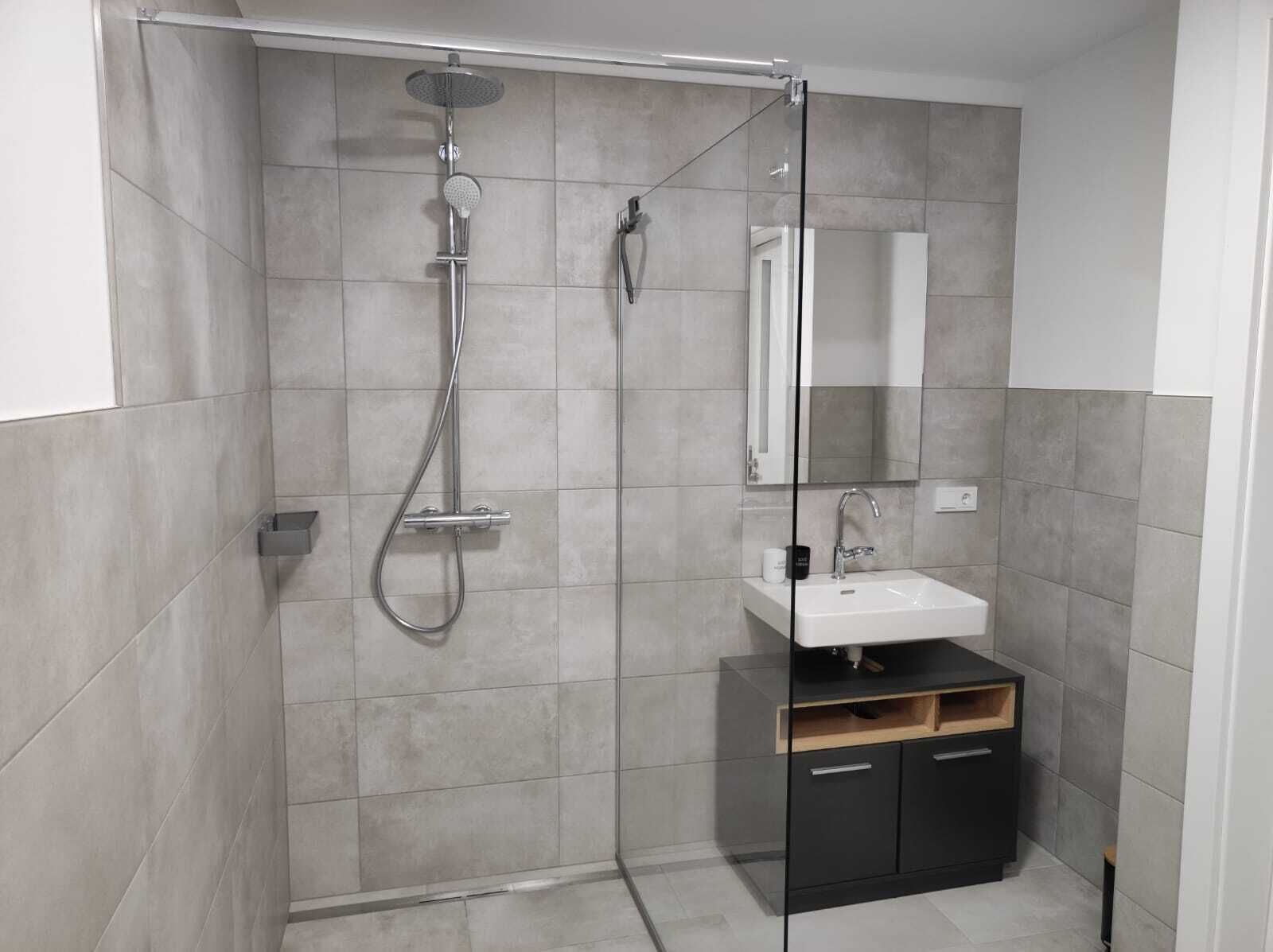 A modern bathroom with a glass-enclosed shower, a white sink, and a black cabinet.