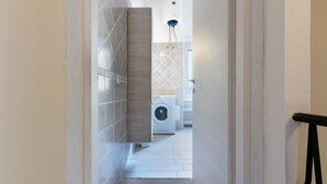 A narrow hallway leading to a laundry area with a washing machine and dryer.