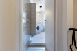 A narrow hallway leading to a laundry area with a washing machine and dryer.