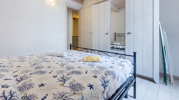 Un dormitorio con cama, techo de madera, puerta blanca y estructura de cama metálica.
