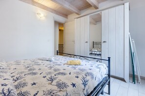 A bedroom with a bed, a wooden ceiling, a white door, and a metal bed frame.