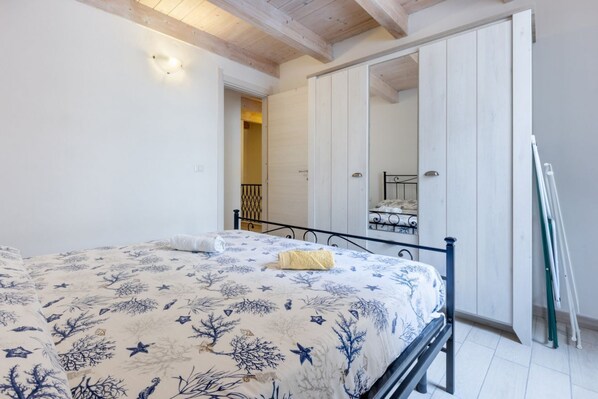 A bedroom with a bed, a wooden ceiling, a white door, and a metal bed frame.