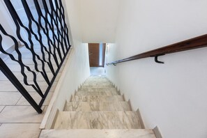 A staircase with a black metal railing, marble steps, and a wooden handrail.