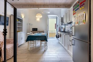 A compact kitchen with a dining area, a refrigerator, and a microwave. - GuestHost- Bright Apartment 250meters from the Sea (Carloforte)