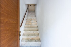 A wooden door leading to a staircase with white walls and a handrail.