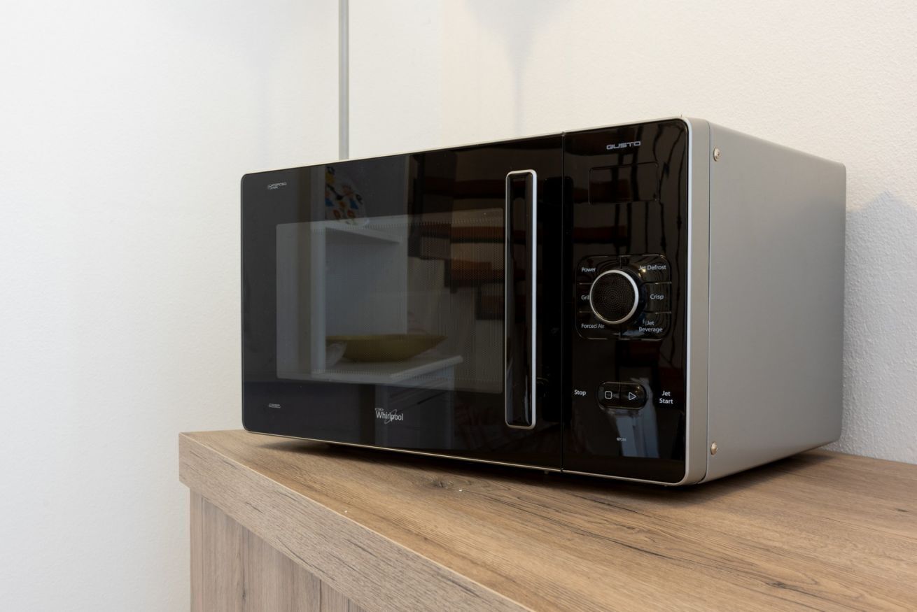 A modern kitchen with a microwave on a wooden countertop.