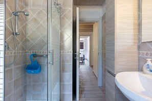 Une salle de bain avec une douche, un lavabo et un porte-savon bleu.