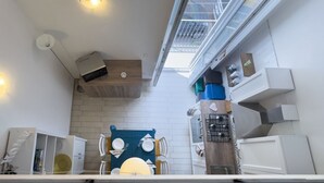 A modern kitchen with a skylight, white walls, and a dining area with a blue tablecloth.