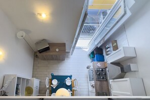 A modern kitchen with a skylight, white walls, and a dining area with a blue tablecloth.