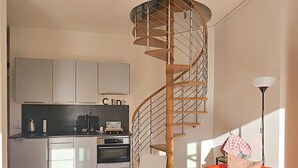 Een moderne keuken met een spiltrap, een rode bank en een lamp.