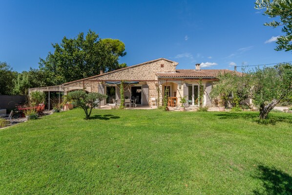 A stone house with a tiled roof, a front porch, and a well-maintained lawn.