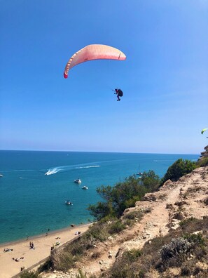 A beach with a clear sky, a person paragliding, and boats in the water. - Lo Cantou" vacation home (Camplong-d'Aude)