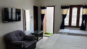 Ein Zimmer mit einer Couch, einem Bett, einem Fernseher und einem Fenster mit Vorhängen.