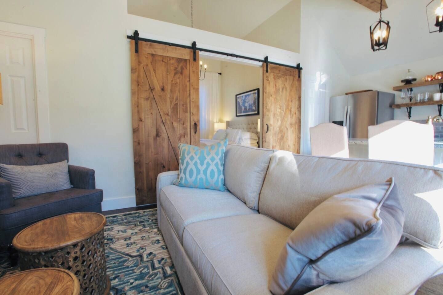 A living room with a sofa, two armchairs, a coffee table, and a wooden sliding door.