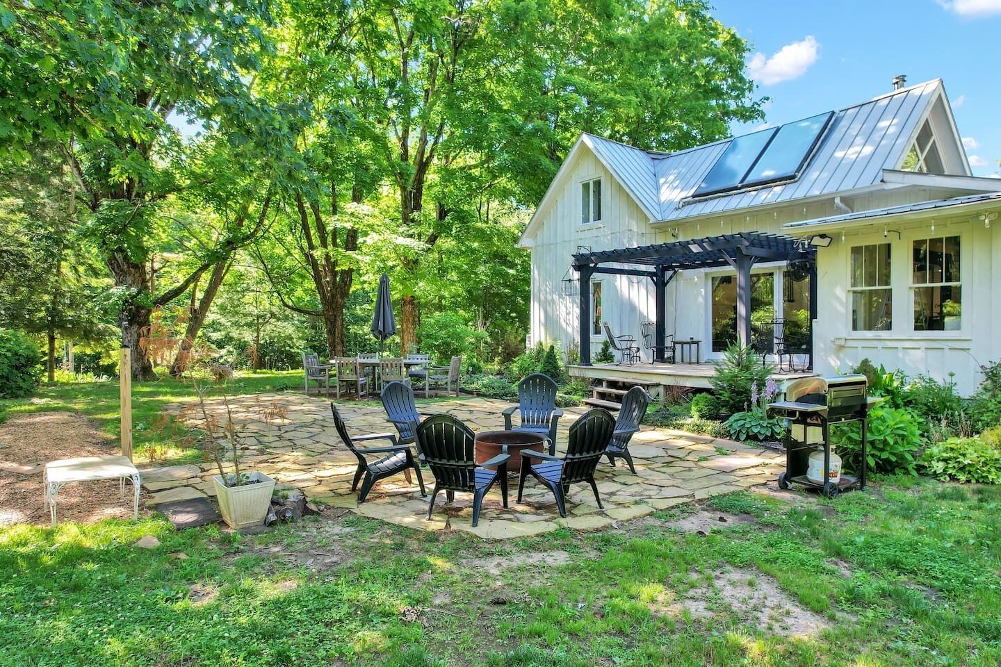 Une maison dotée d’un patio couvert, d’un espace salon extérieur et d’un coin barbecue.