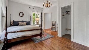 Ein Schlafzimmer mit Himmelbett, einer Kristallleuchtre, Holzboden und Blick ins Freie.