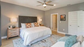 A bedroom with a bed, nightstands, a ceiling fan, and a door.