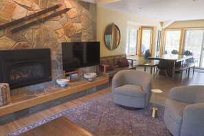 A stone fireplace with a TV, seating area, and dining space.