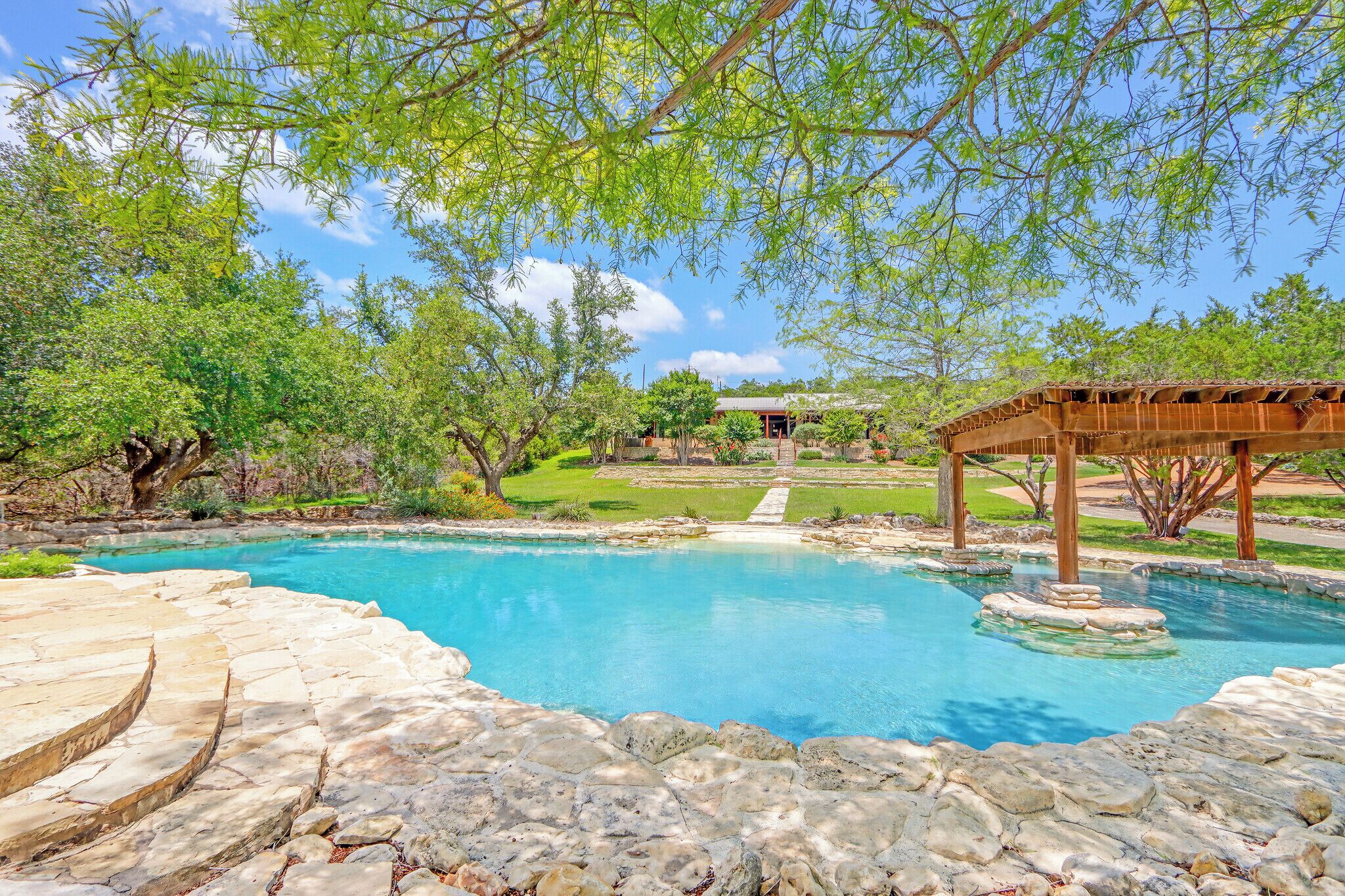 Soak up the Texas sun in your own private oasis—natural stone pool, shaded pergola, and lush greenery create the perfect Hill Country escape